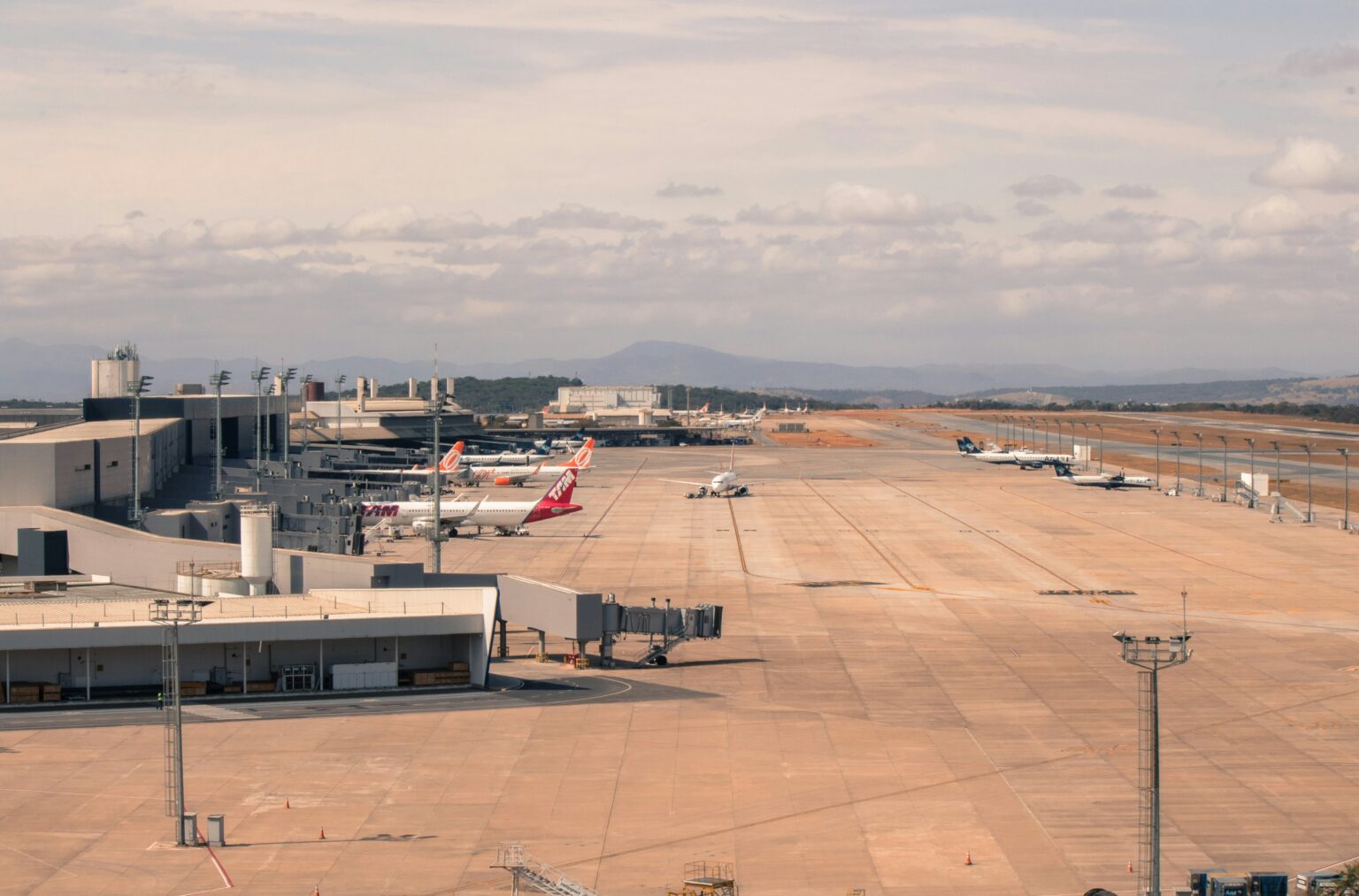EuroAirport Basel Mulhouse Freiburg (BSL / LFSB): aircraft parked at terminal gates on a wide apron with mountains behind