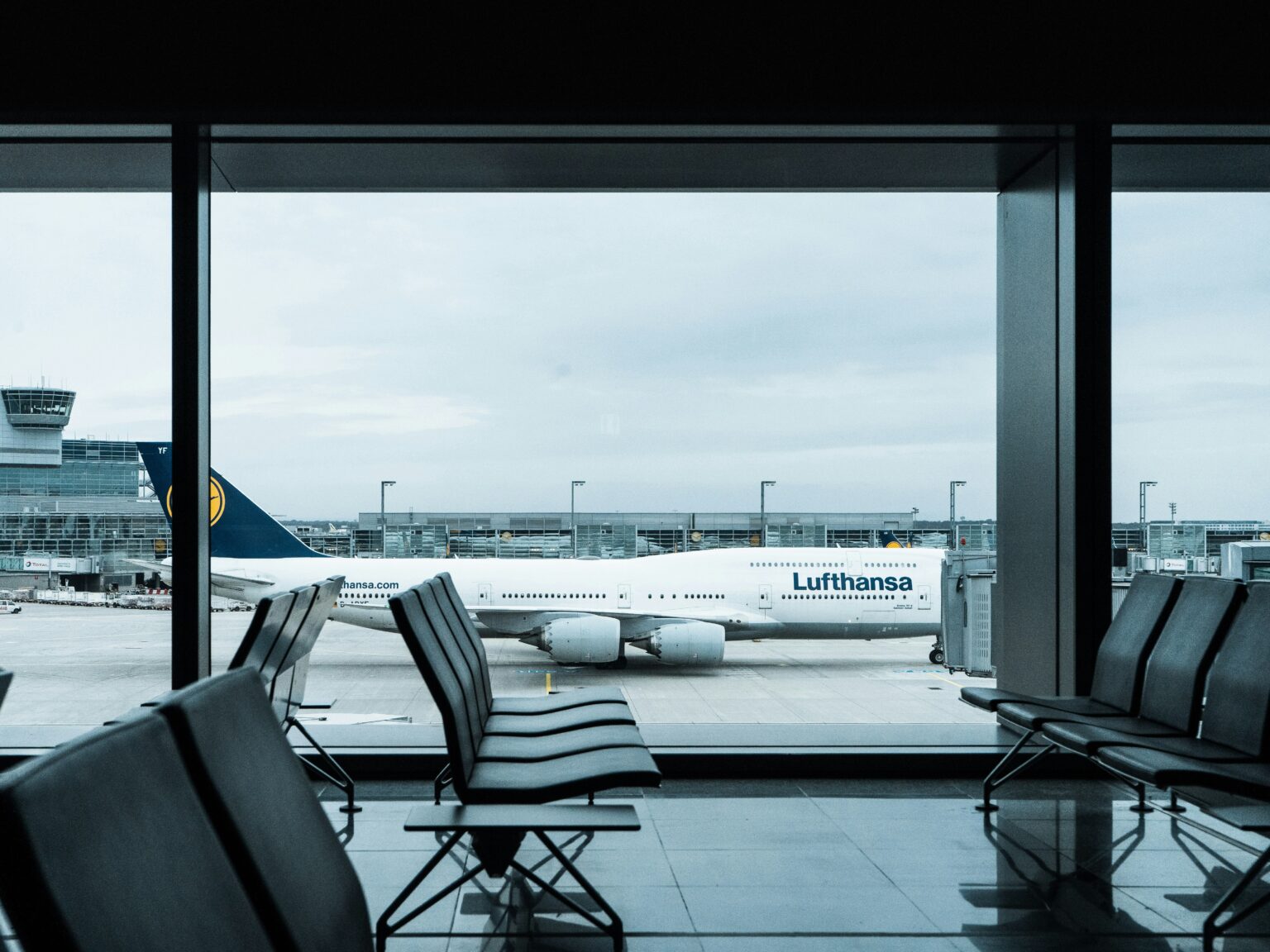 Zayed International Airport (AUH / OMAA): view from inside a terminal lounge across the apron to a parked airliner