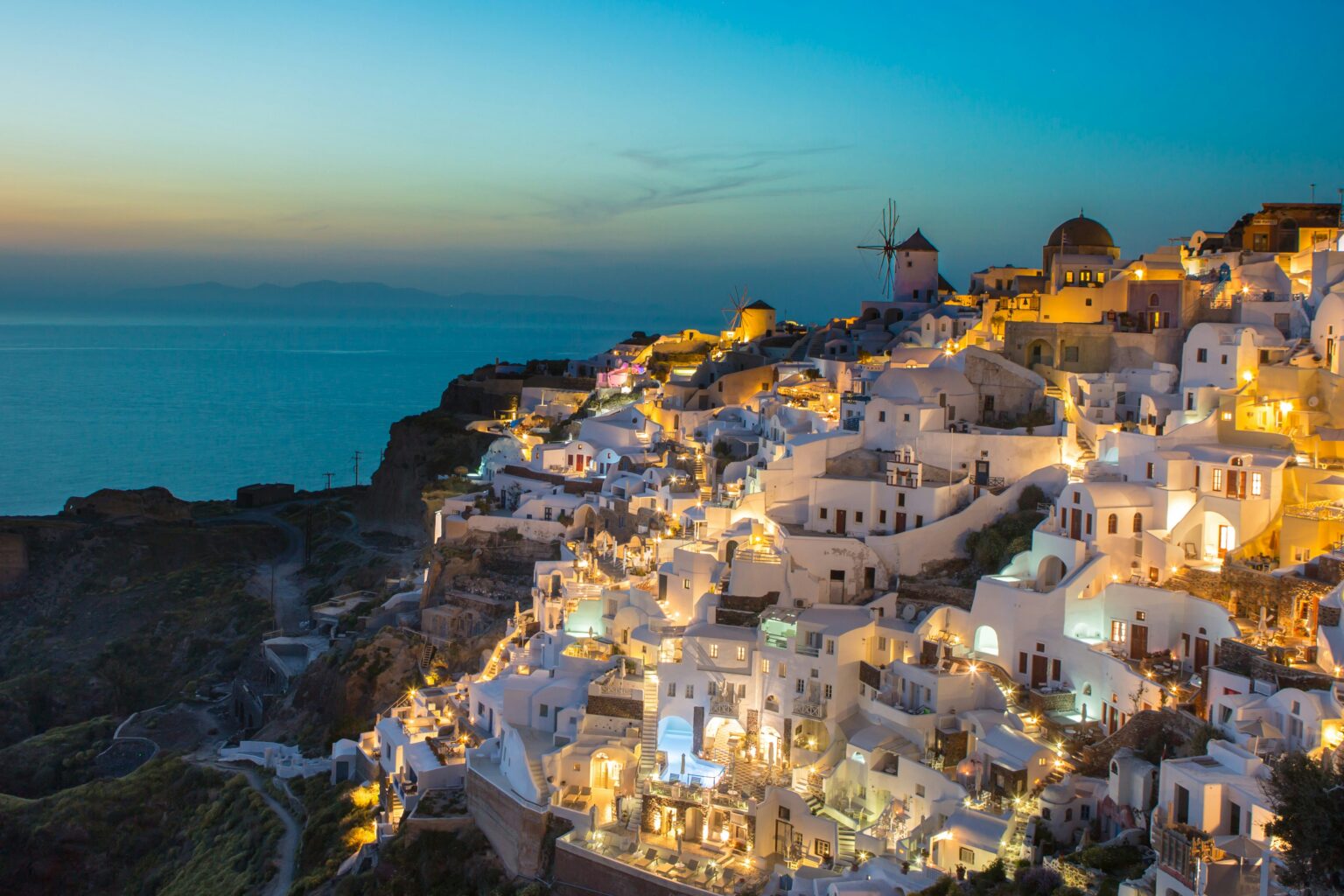 Santorini International Airport (JTR / LGSR): santorini caldera villages lit up at dusk